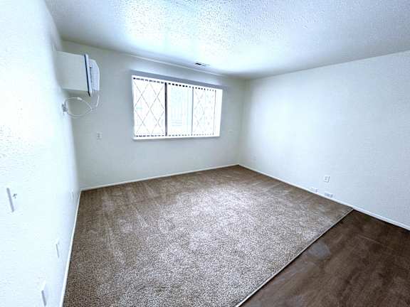 A living room with a window and a carpeted floor.