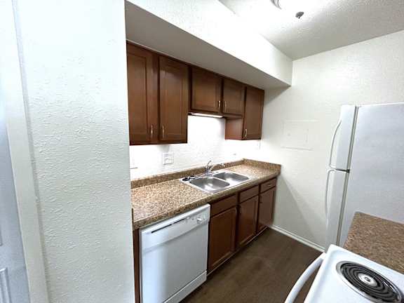 A kitchen with brown cabinets and white appliances.