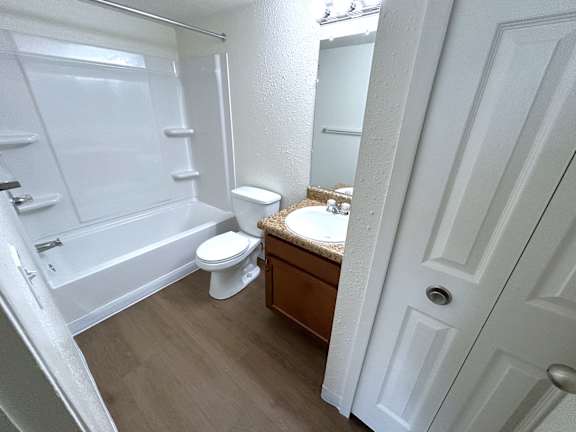 A white toilet sits in a bathroom next to a bathtub.