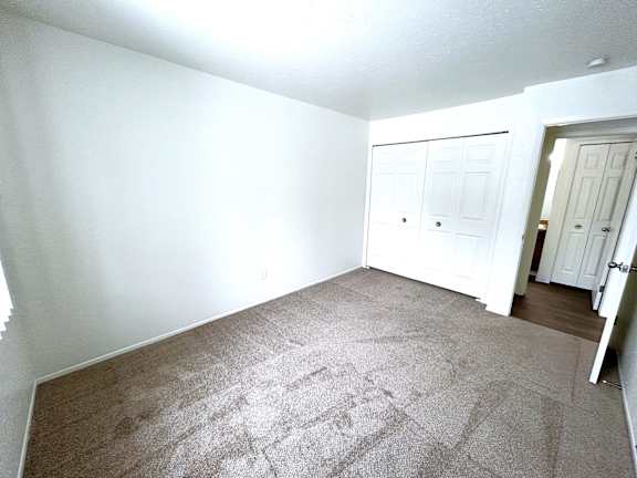 A bedroom with a carpeted floor and a white door.