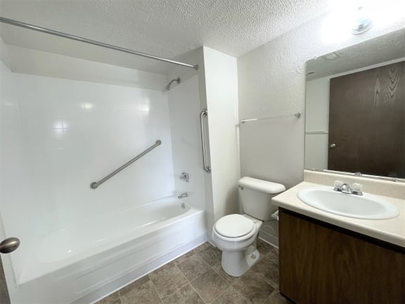 Accessible bathroom with grab bars and white fixtures at Charter Oaks Apartments, Davison