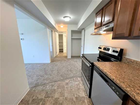 Galley kitchen with granite countertop and dark cabinets at Charter Oaks Apartments, Michigan