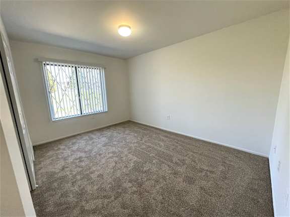 Empty carpeted bedroom with window and vertical blinds 1 at Charter Oaks Apartments, Michigan, 48423