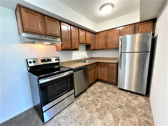 Lshaped kitchen with stainless steel appliances and tile flooring at Charter Oaks Apartments, Davison, 48423