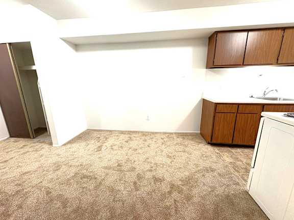A dining area with a white dishwasher and brown cabinets.