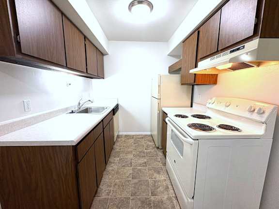 A kitchen with a white stove and brown cabinets.
