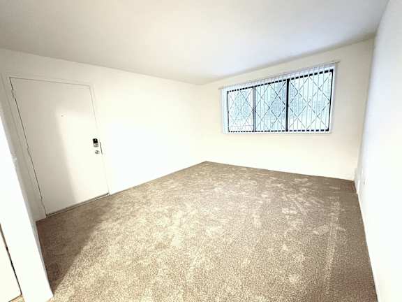 A living room with a carpeted floor and a window with bars.