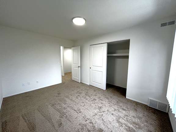 Empty carpeted bedroom with open closet and doorway 2 at Charter Oaks Apartments, Davison, 48423