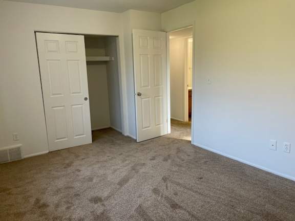 Empty carpeted bedroom with closet and hallway at Charter Oaks Apartments, Michigan, 48423