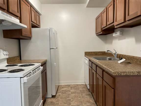 Compact kitchen with white appliances and granite countertops at Charter Oaks Apartments, Davison, 48423