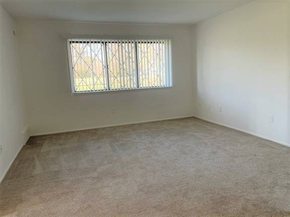 Empty carpeted bedroom with window and vertical blinds at Charter Oaks Apartments, Davison, 48423