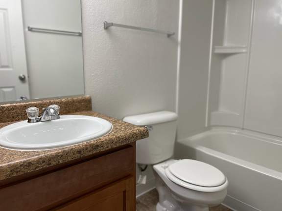 Bathroom with white fixtures and granite vanity at Charter Oaks Apartments, Davison, MI