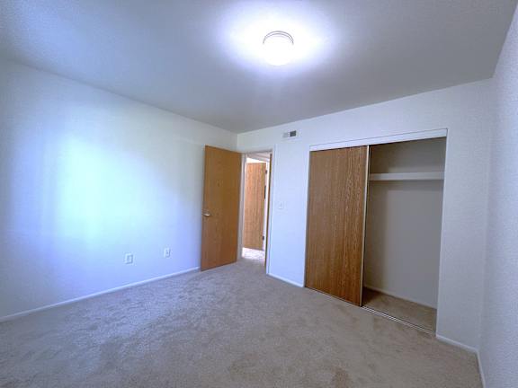 Empty carpeted bedroom with open closet and doorway 5 at Charter Oaks Apartments, Michigan, 48423