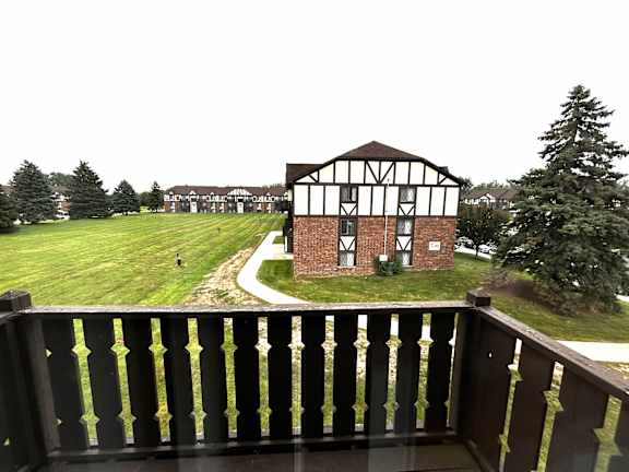 Courtyard view from private balcony with dark wood railing at Charter Oaks Apartments, Davison, Michigan