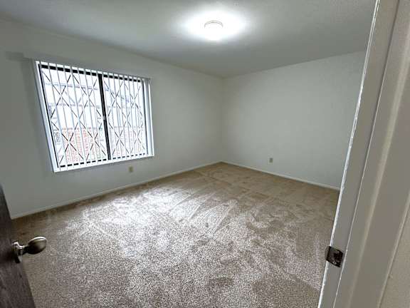 Empty carpeted bedroom with barred window at Charter Oaks Apartments, Davison, MI, 48423