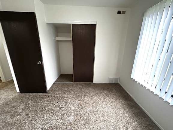 Bedroom with closet and white vertical blinds at Charter Oaks Apartments, Michigan