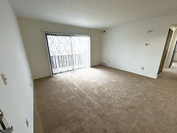 Spacious carpeted living room with sliding glass door 1 at Charter Oaks Apartments, Michigan