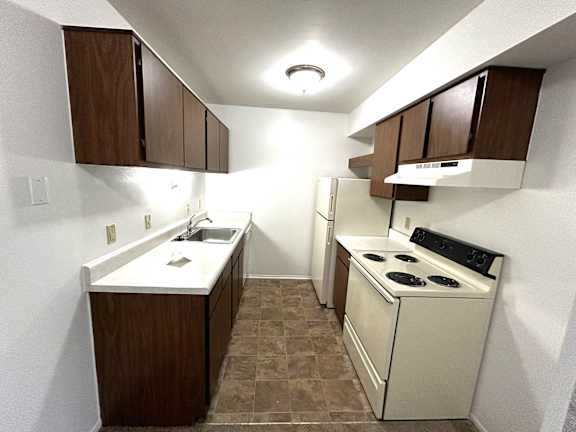 Galley kitchen with coil stove and white countertops at Charter Oaks Apartments, Davison, MI