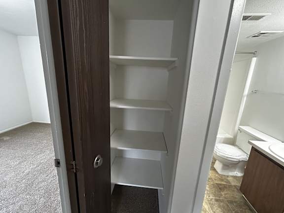 Linen closet with white shelving and wood door at Charter Oaks Apartments, Davison, MI, 48423