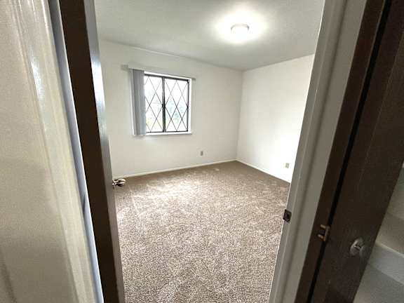 Empty carpeted bedroom with security window and ceiling light at Charter Oaks Apartments, Davison, 48423