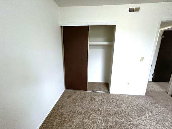 Empty carpeted bedroom with sliding closet door at Charter Oaks Apartments, Michigan, 48423
