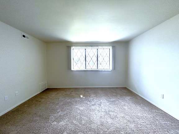 A living room with a window and carpeted floor.