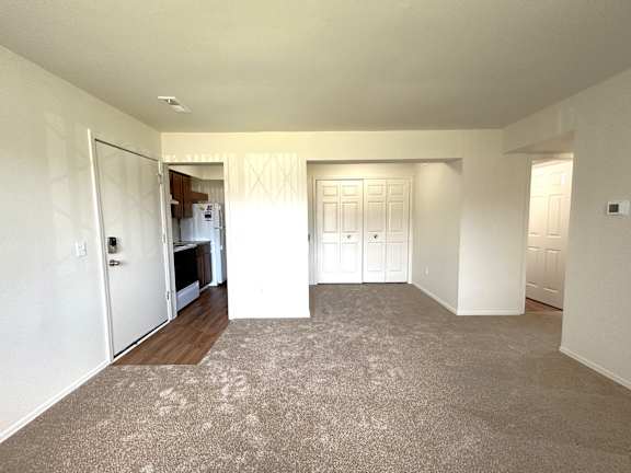A spacious living room with a carpeted floor and white walls.