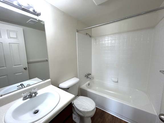 A white bathroom with a toilet, sink, and bathtub.
