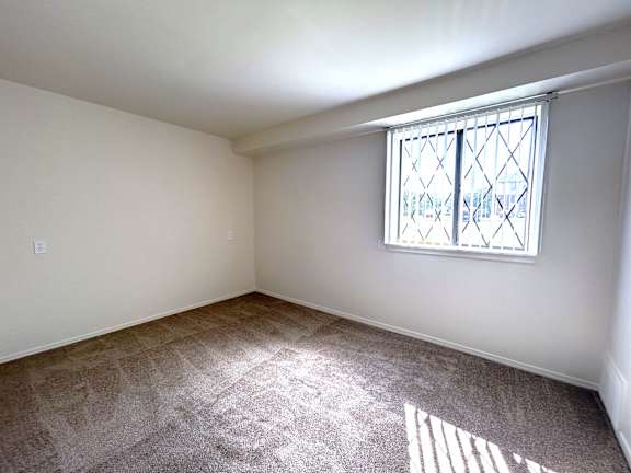 A bedroom with a window and carpeted floor.