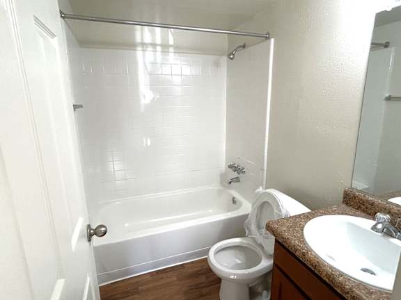 A white toilet is in a bathroom with a white tub and sink.