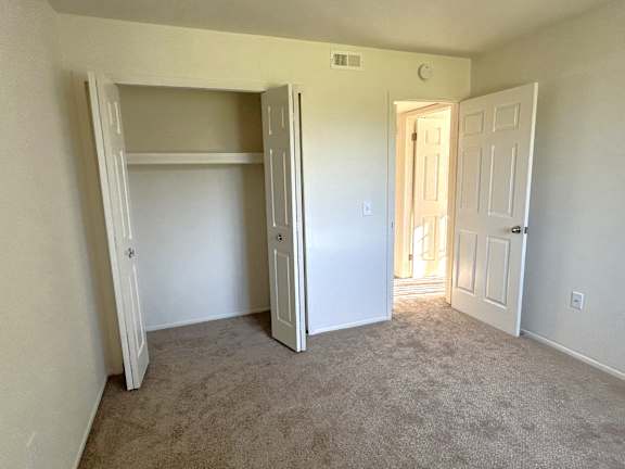 A bedroom with a carpeted floor and a white door.
