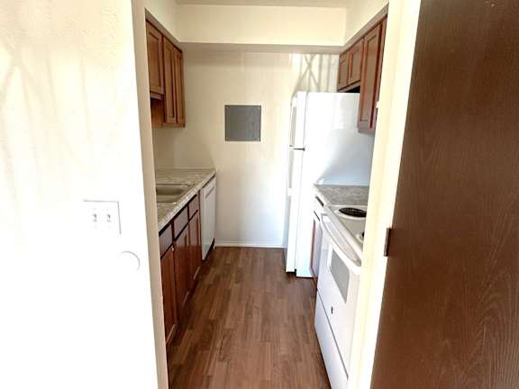 A kitchen with a white fridge and wooden cabinets.