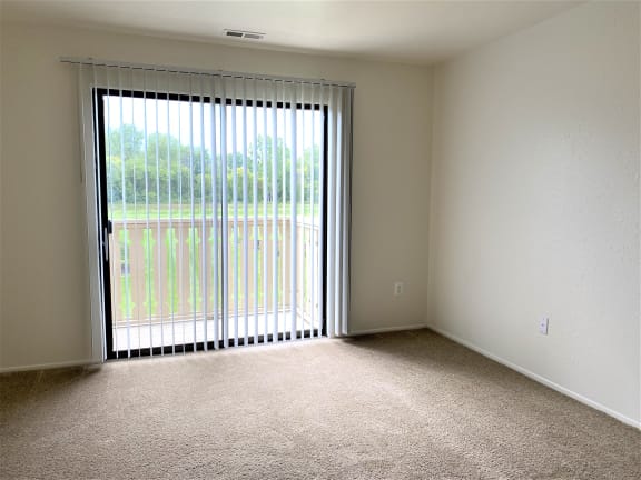 an empty living room with a large sliding glass door at Huntington Place Apartments, Michigan, 48732
