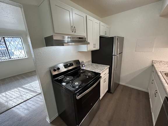 A kitchen with a black stove top oven and a black refrigerator.