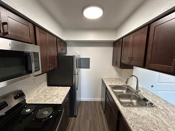 A kitchen with dark brown cabinets and a black refrigerator.