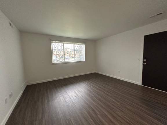 Spacious living room with vinyl plank flooring and a window.