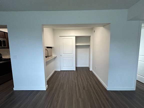 A dining room with a white door and a brown floor.