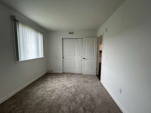 A bedroom with a carpeted floor and a white door.