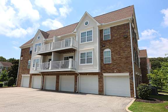 A two-story brick house with a balcony on the second floor.