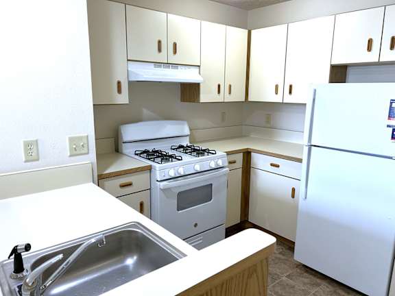 A kitchen with a white stove and a white refrigerator.