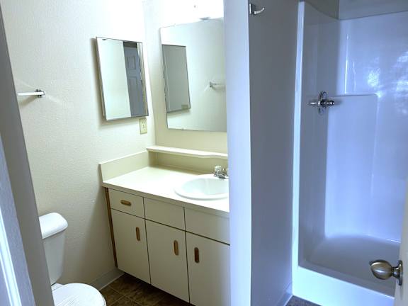 A white bathroom with a toilet, sink, and mirror.