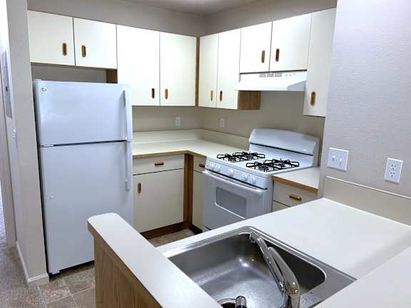 A kitchen with a white refrigerator, stove, and sink.