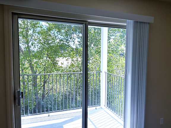 A patio door with a view of a tree-lined balcony.