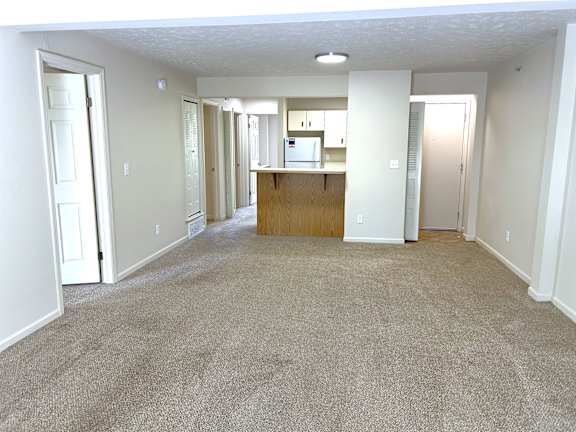 A spacious living room with a kitchen in the background.
