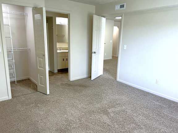 A white bedroom with a carpeted floor and a white door.