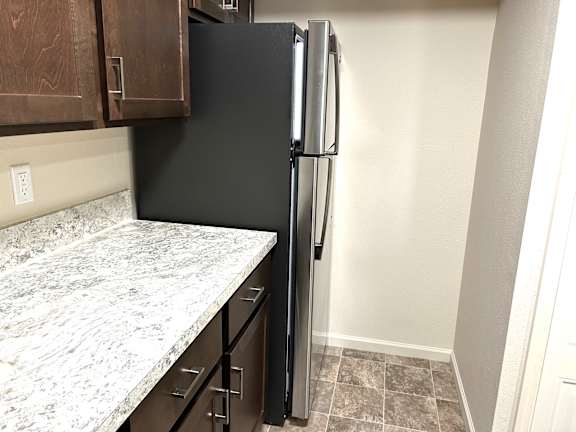 Kitchen with granite countertop and black refrigerator at Heatherwood Apartments, Grand Blanc