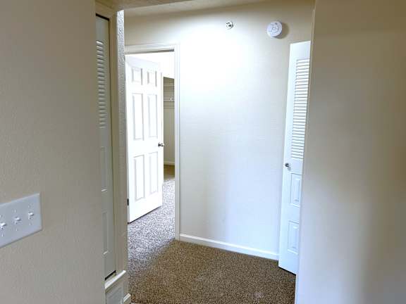 Carpeted hallway with open bedroom door and closet at Heatherwood Apartments, Michigan, 48439