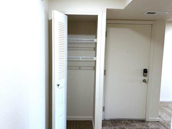Entry foyer with coat closet and wire shelving at Heatherwood Apartments, Grand Blanc, MI 48439