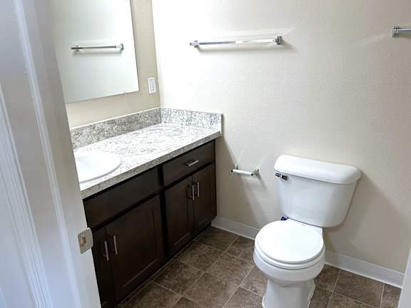 Bathroom with granite vanity and dark wood cabinets at Heatherwood Apartments, Grand Blanc, MI