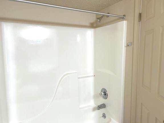 White tub shower combo with grab bar and chrome fixtures at Heatherwood Apartments, Grand Blanc, Michigan